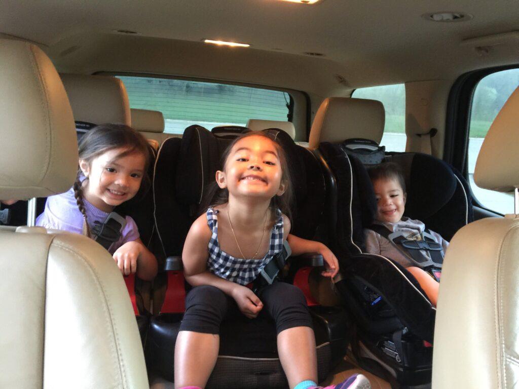 Kids sitting in the back of a minivan on a roadtrip