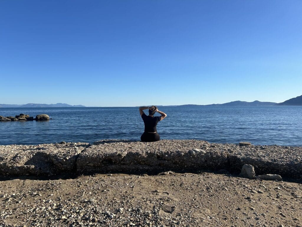 Letisha sitting on a rock ledge overlooking a body of water